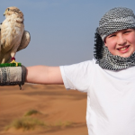 A Trawey Tours guest in traditional headwear holds a falcon during an included photography session, illustrating our transparent pricing.