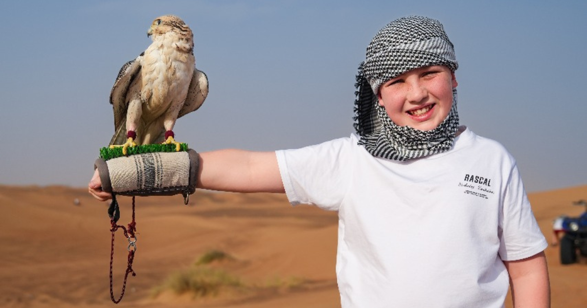 A Trawey Tours guest in traditional headwear holds a falcon during an included photography session, illustrating our transparent pricing.