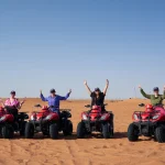 Group of happy women friends posing on red quad bikes during a thrilling desert safari adventure in Dubai with Trawey Tours.