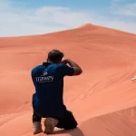 Trawey guide taking guest photo in red sand