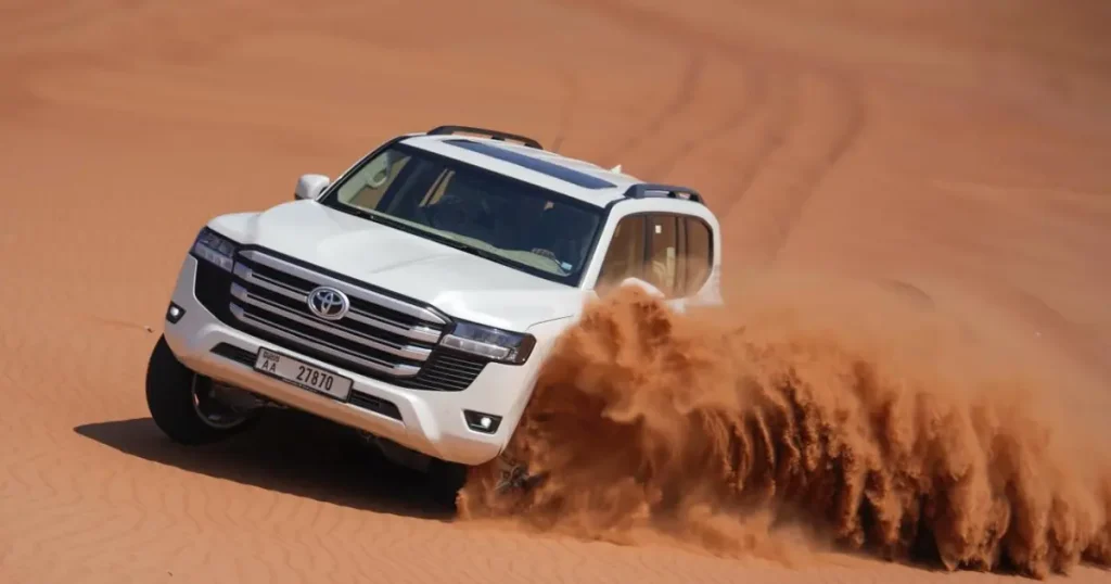 Licensed Trawey Tours driver performing a controlled dune bashing maneuver in a white Land Cruiser.