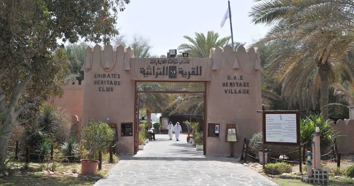 The stone entrance gate of the Emirates Heritage Club and UAE Heritage Village in Abu Dhabi surrounded by palm trees.