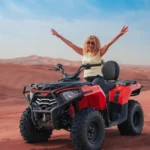 A woman enjoying an adventurous quad bike ride across the red sand dunes during a Dubai desert safari.