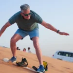 Active senior man enjoying a luxury desert sandboarding tour; adventure travel for retirees and silver surfers.